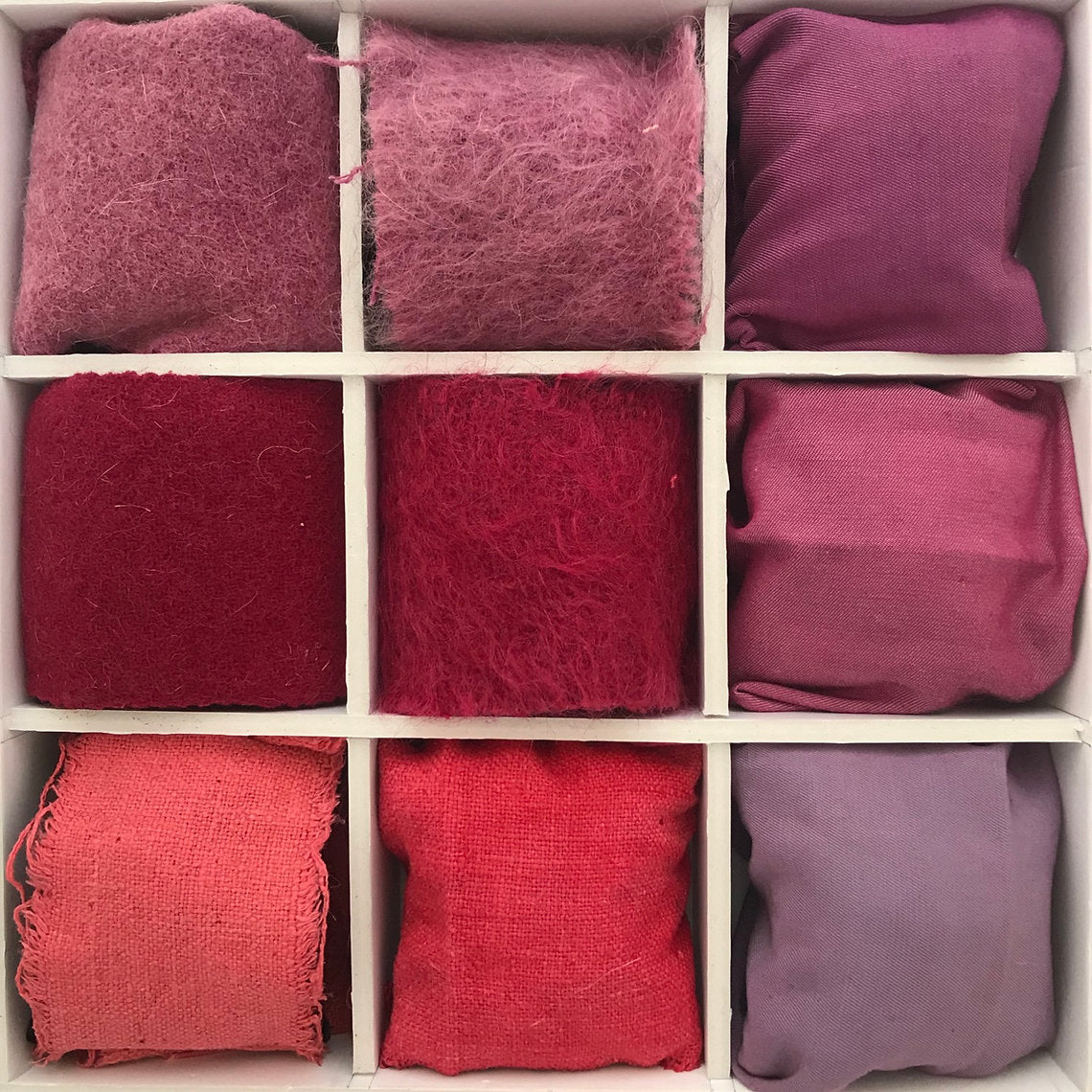 Nine fabric swatches in various shades of red and purple arranged in a grid.