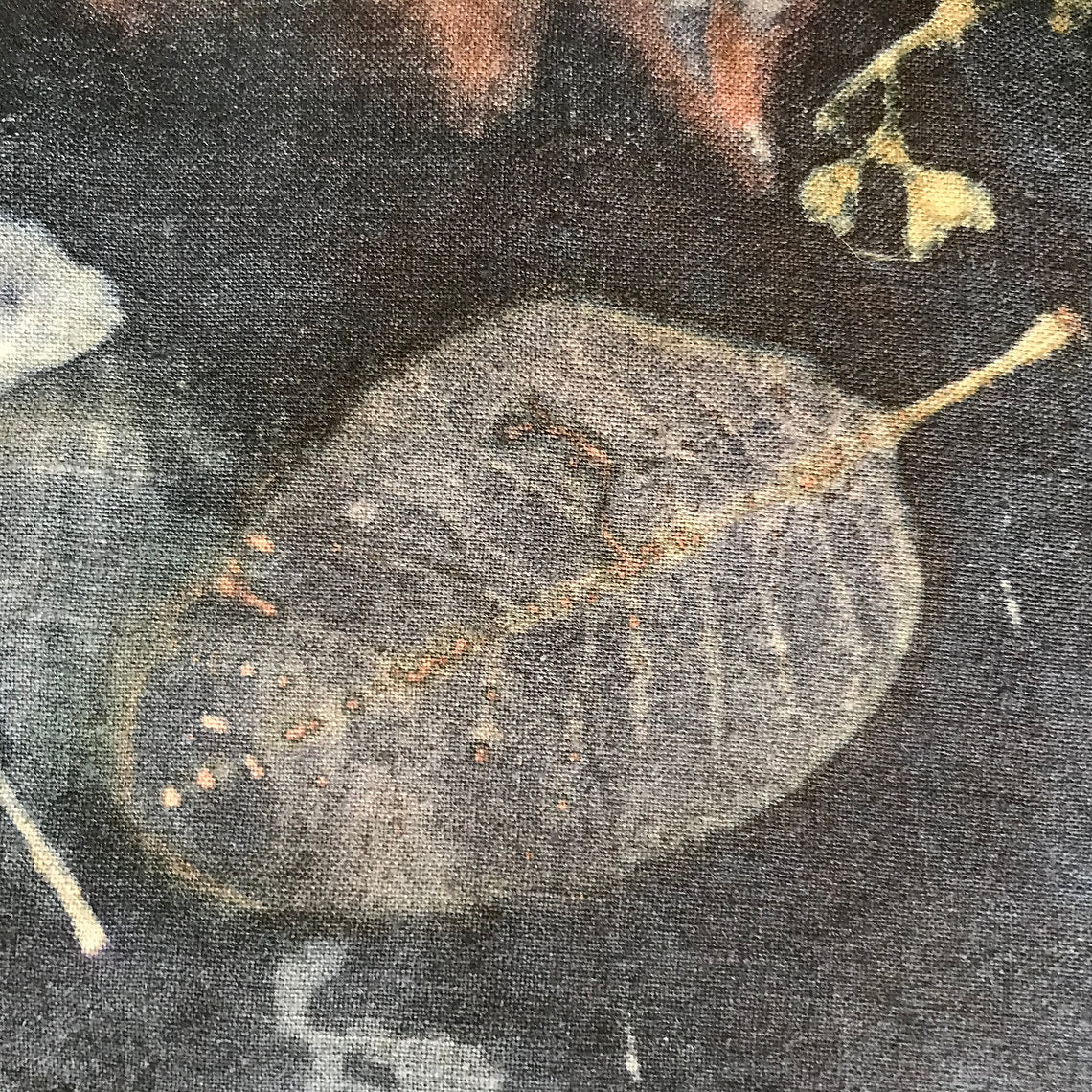 Close-up of a textured fabric with a large gray leaf-like shape and smaller elements.