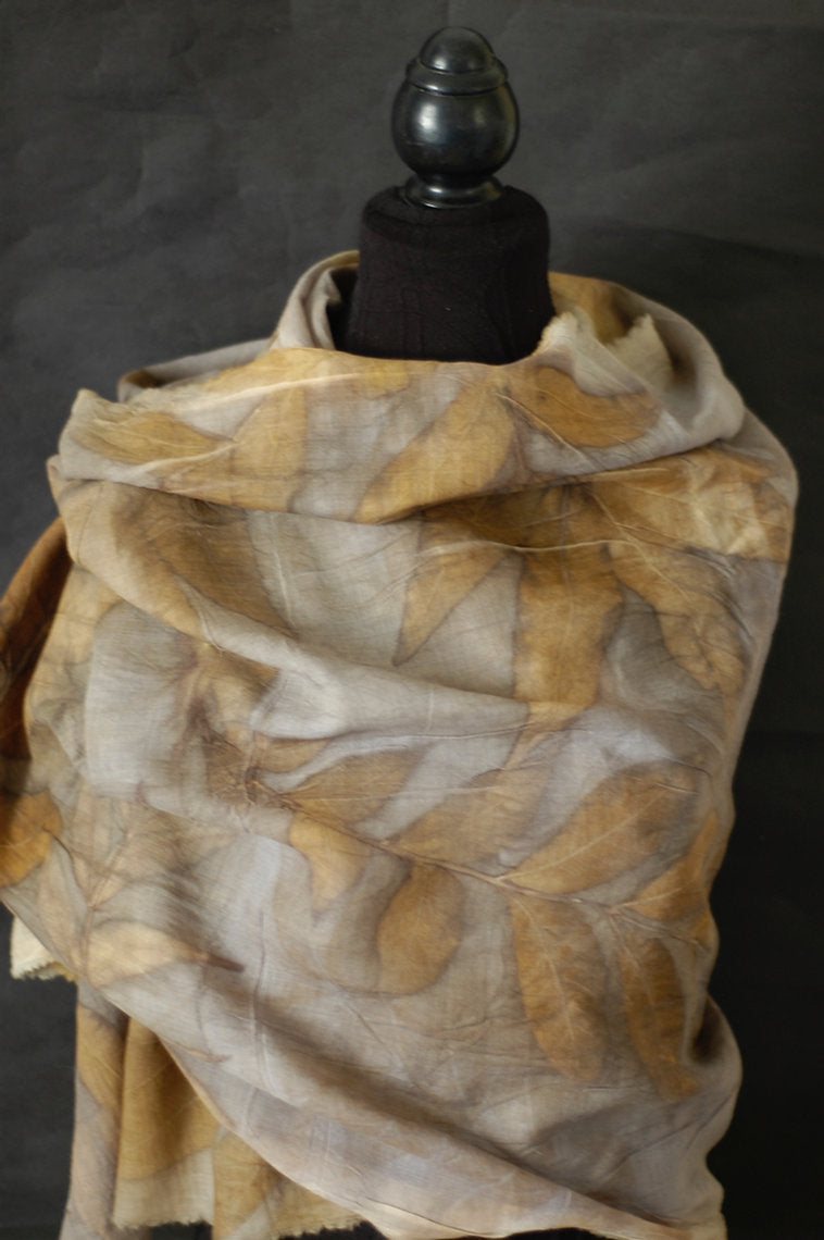 Scarf with leaf pattern draped over a mannequin against a dark background