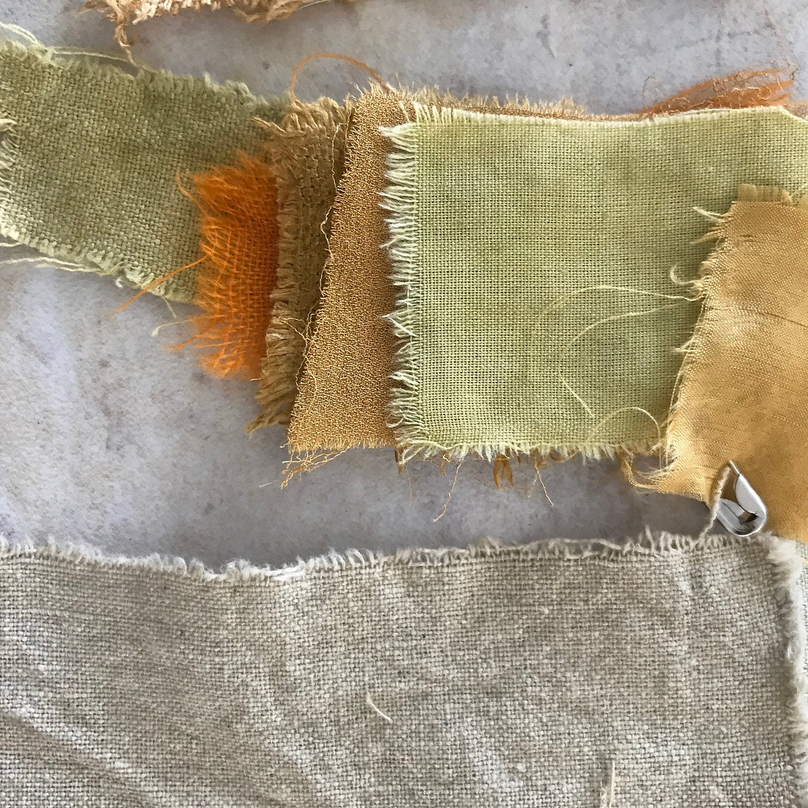 Fabric swatches in green, orange, and brown on a textured surface