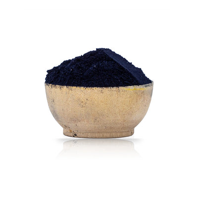 Navy blue powder in a beige bowl on a white background