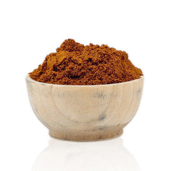Wooden bowl filled with red powder on a white background