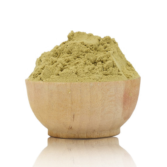 Wooden bowl filled with green powder on a white background