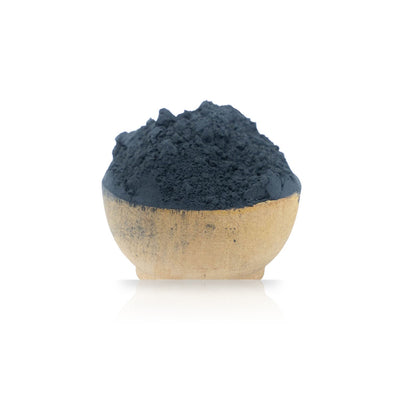 Ceramic bowl filled with dark blue Woad Powder (Isatis Tinctoria) on a white background