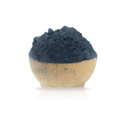 Ceramic bowl filled with dark blue Woad Powder (Isatis Tinctoria) on a white background