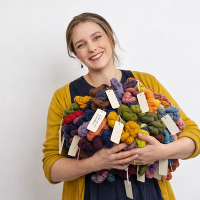 Woman holding a colorful bouquet of yarn with price tags against a white background