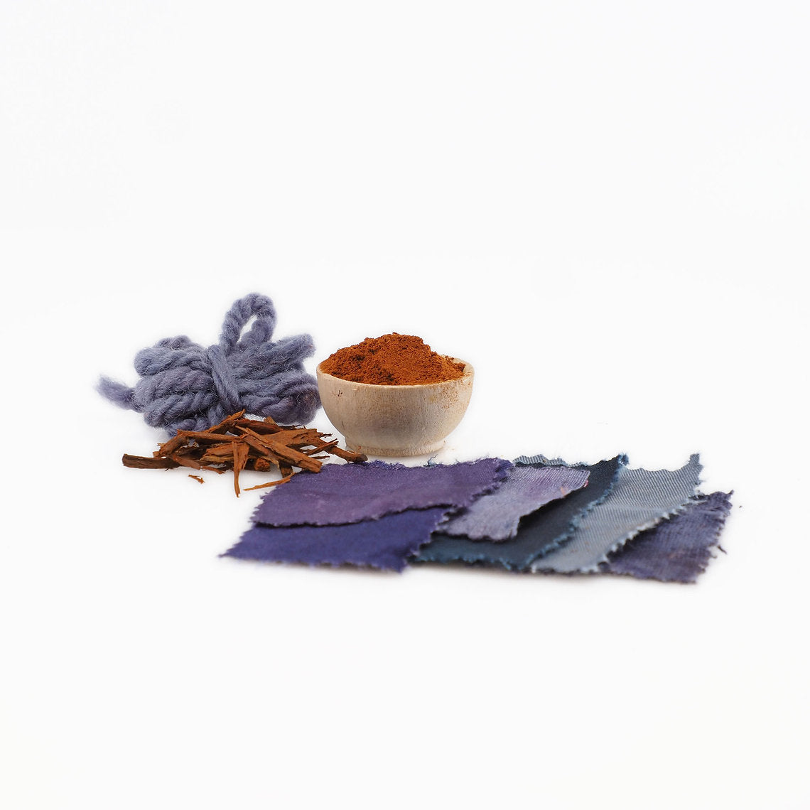 Logwood Chips (Haematoxylum campechianum) powder and and fabric swatches dyed with this on a white background