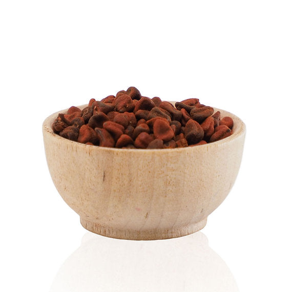 Wooden bowl filled with red seeds on a white background