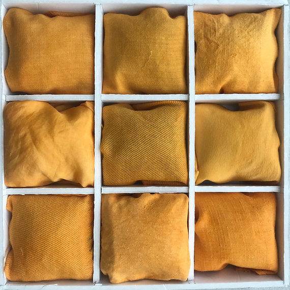 Nine mustard yellow cushions arranged in a 3x3 grid on a white background.
