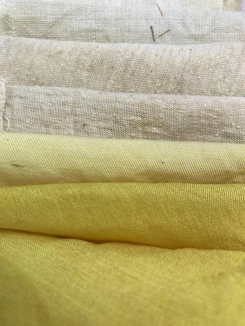 Stack of fabric swatches in beige, gray, and yellow.