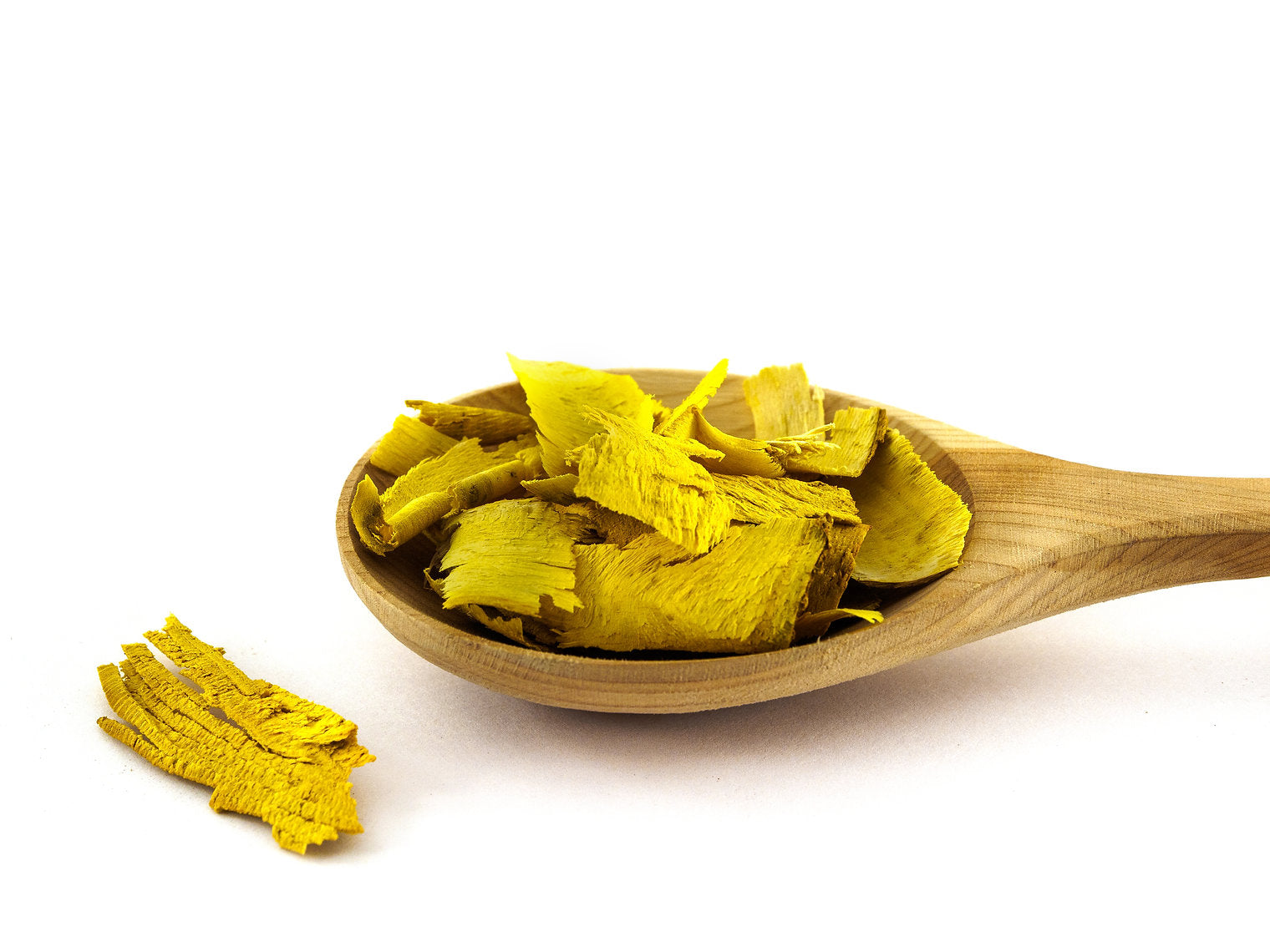 Wooden spoon filled with yellow dried leaves on a white background