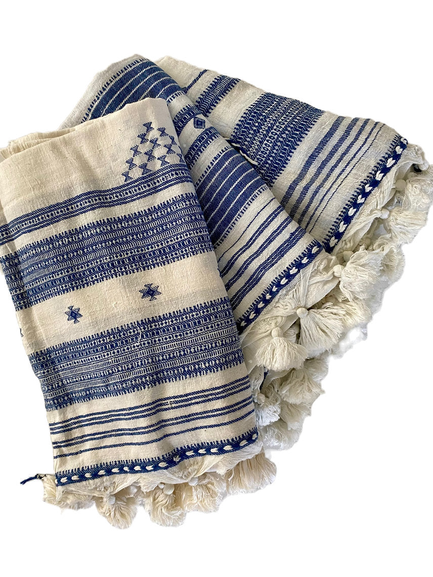 Blue and white patterned blanket with tassels on a white background