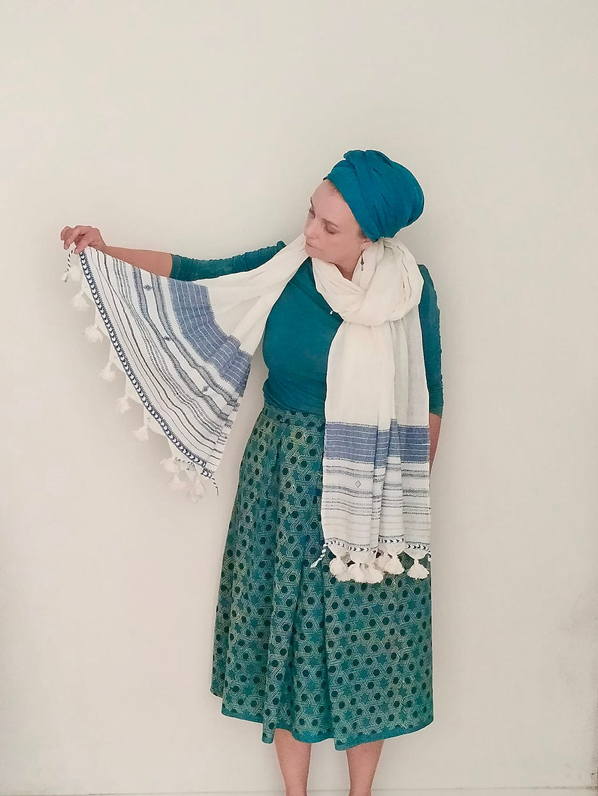 Woman holding a patterned shawl against a plain background
