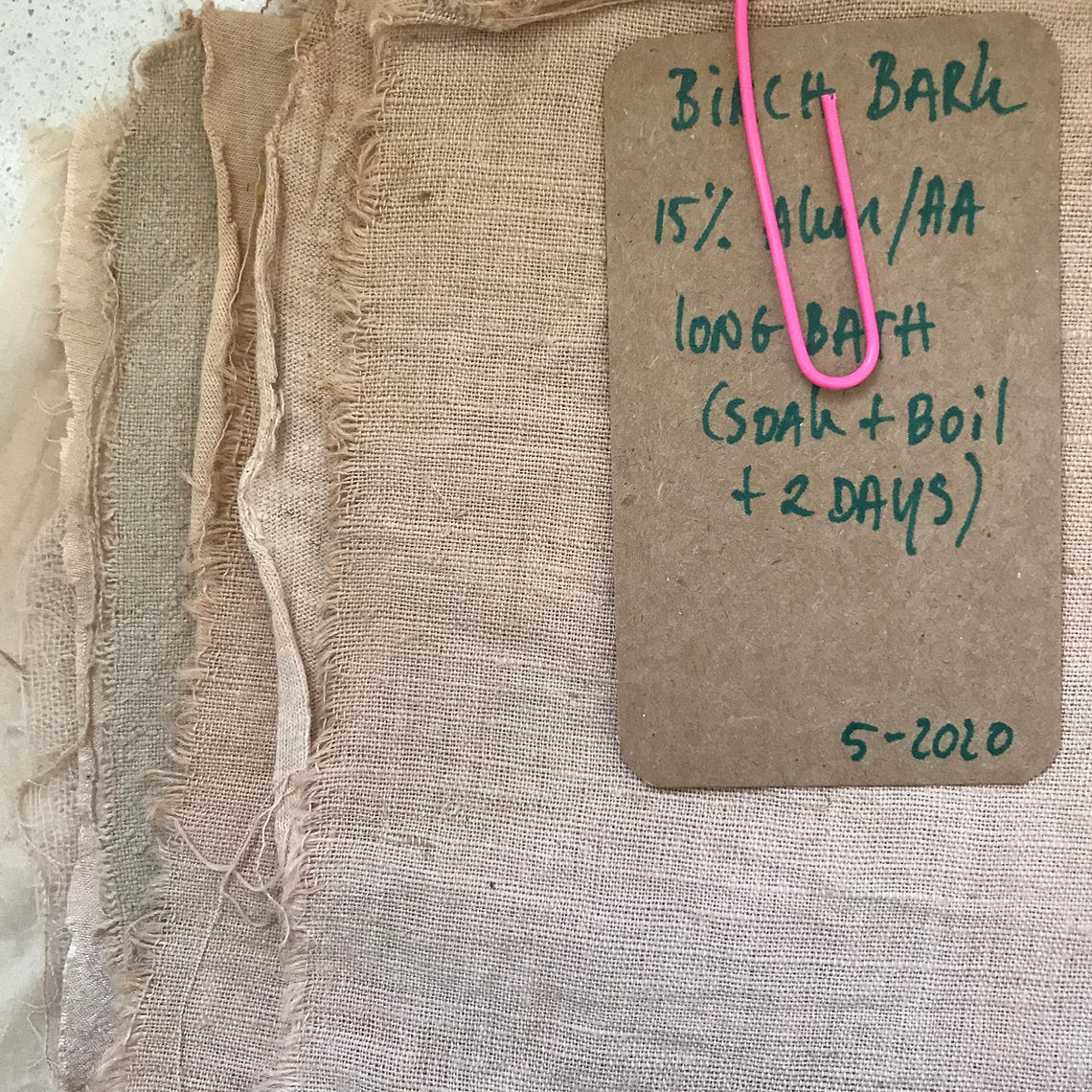 Birch bark with a label detailing its treatment method on a textured surface.