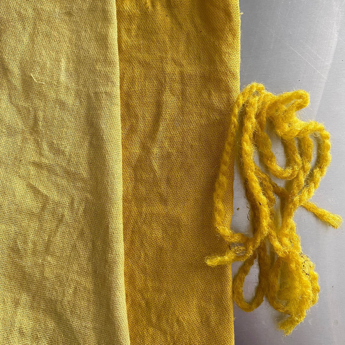 Yellow fabric with a bundle of yellow yarn on a gray surface