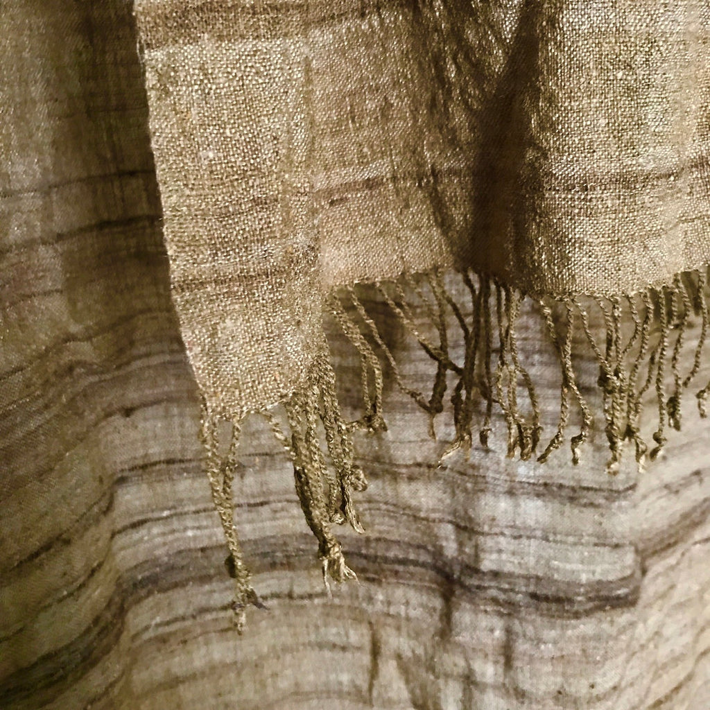 Textured brown silk scarf with fringes on a wooden surface