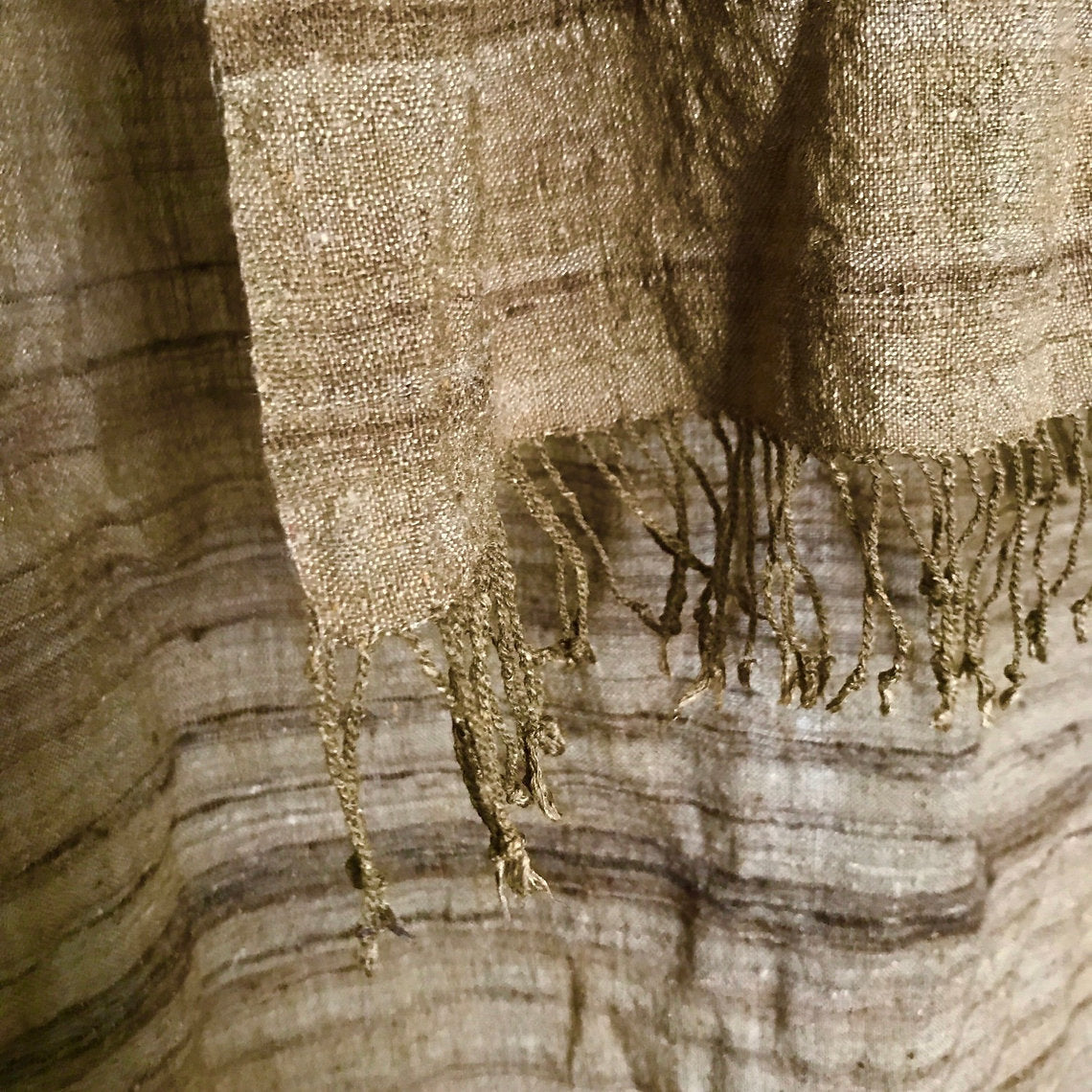 Textured brown silk scarf with fringes on a wooden surface