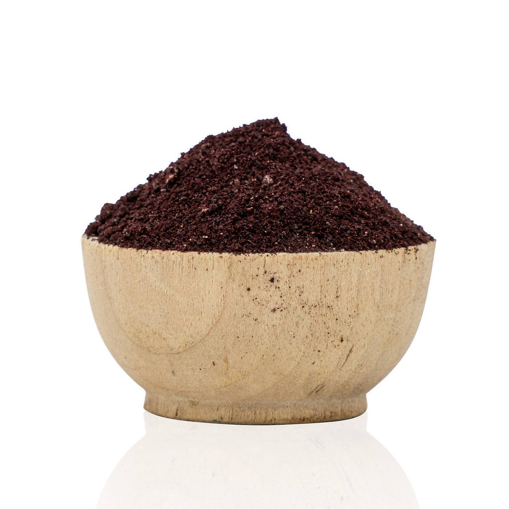 Wooden bowl filled with Cochineal Powder (Dactylopius coccus) organic dark brown ground on a white background