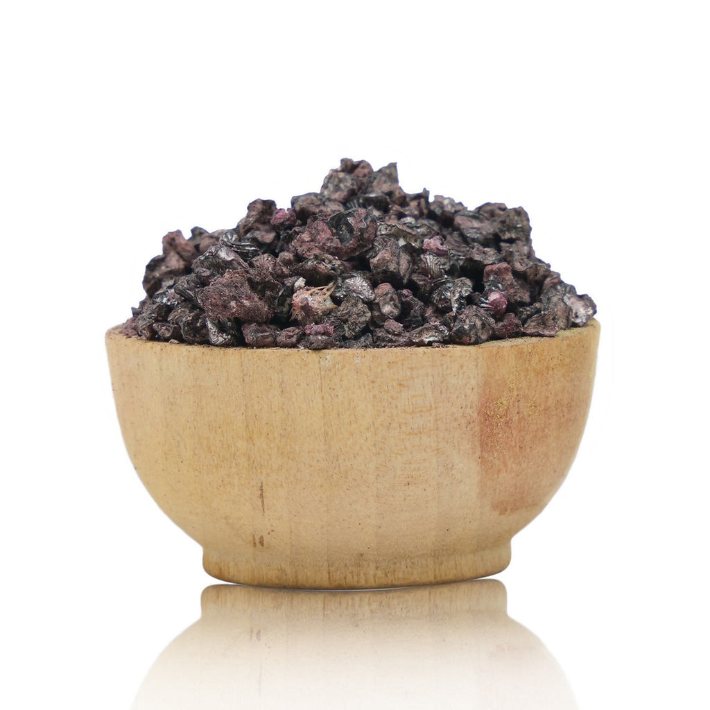 Wooden bowl filled with dark-colored stones on a white background