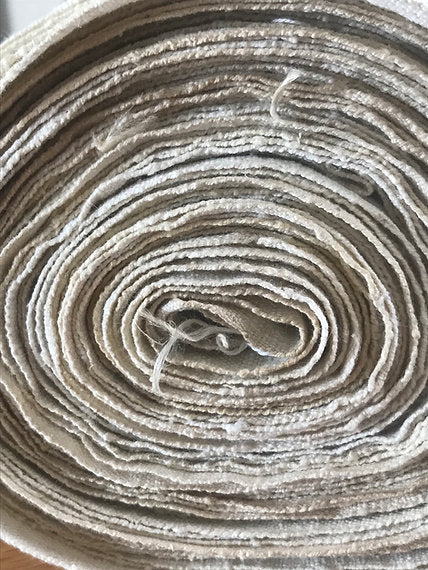 Close-up of a roll of beige fabric with visible texture