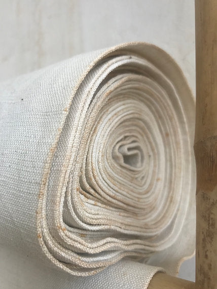 Close-up of a roll of beige fabric on a wooden surface