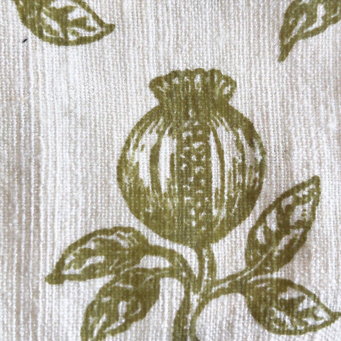 Close-up of a fabric pattern with green floral design on beige background