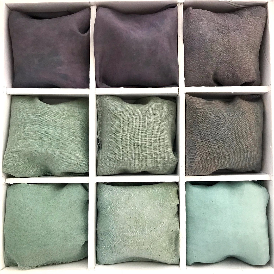 Nine indigo blue green fabric samples dyed Green Indigo Powder (Indigofera Tinctoria)  in various colors arranged in a grid on a white background