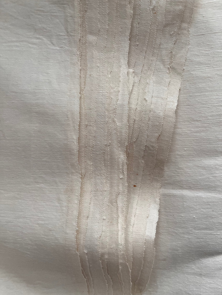 Close-up of a textured white fabric with a visible seam.