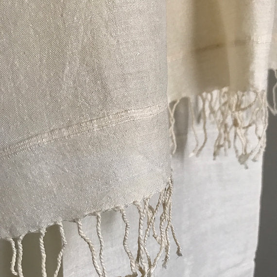Close-up of a beige fabric with fringes on a light background