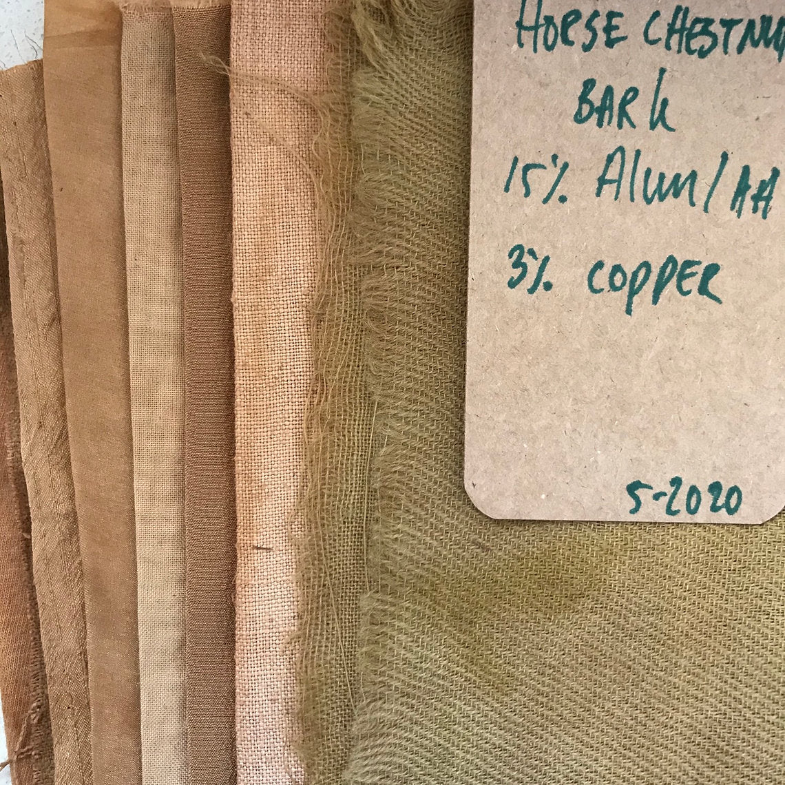 Textured fabric swatches dyed Horse Chestnut Bark (Aesculus hippocastanum) with a label on a white background