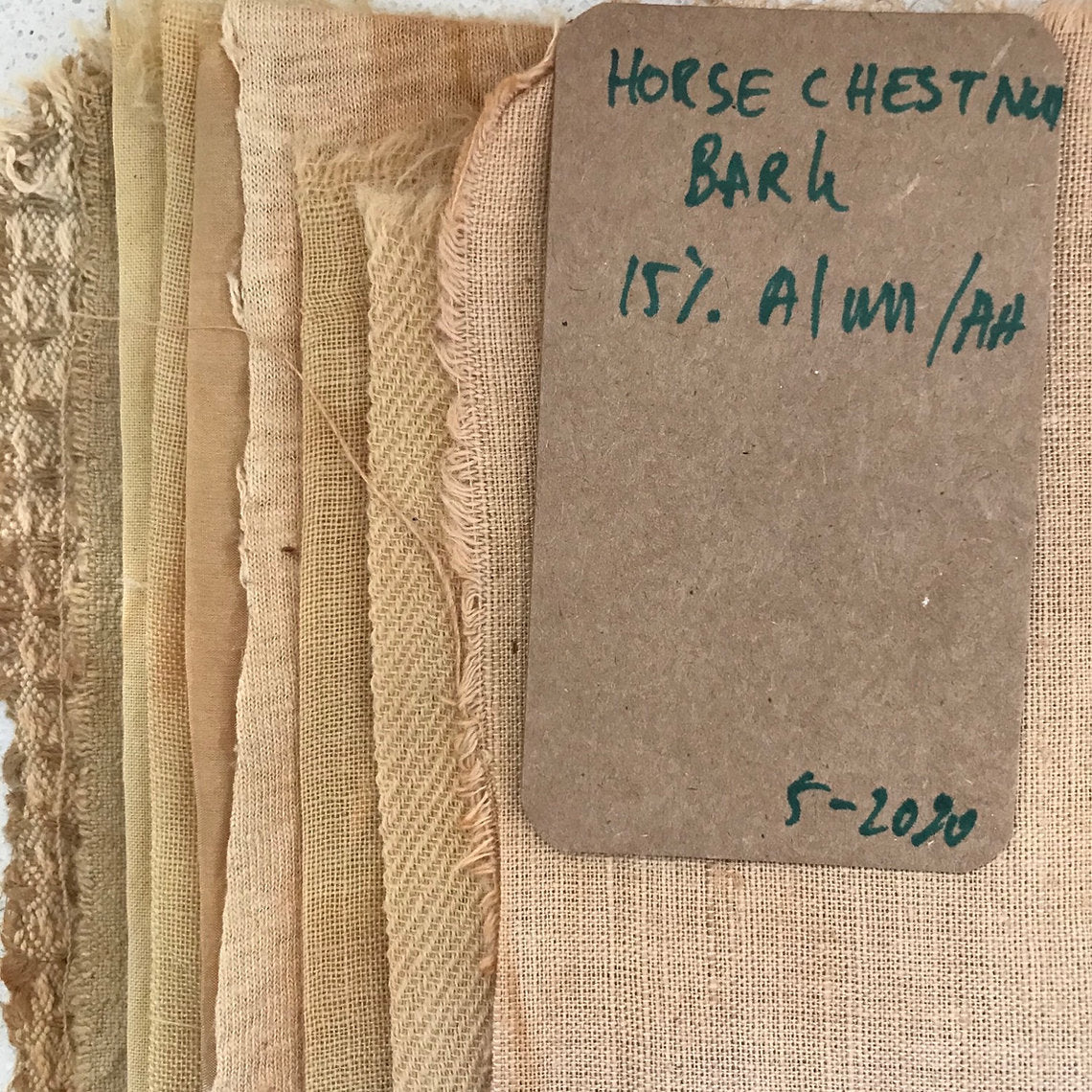 Collection of fabrics dyed horse chestnut bark samples with a label on a textured background