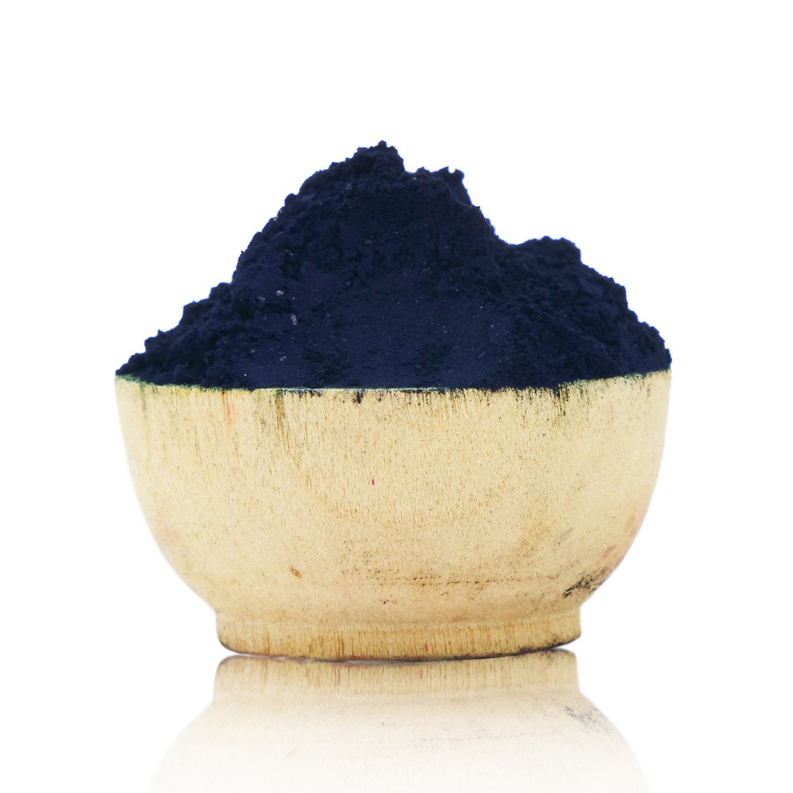 Wooden bowl filled with dark blue powder on a white background