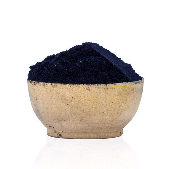 Navy blue powder in a beige bowl on a white background