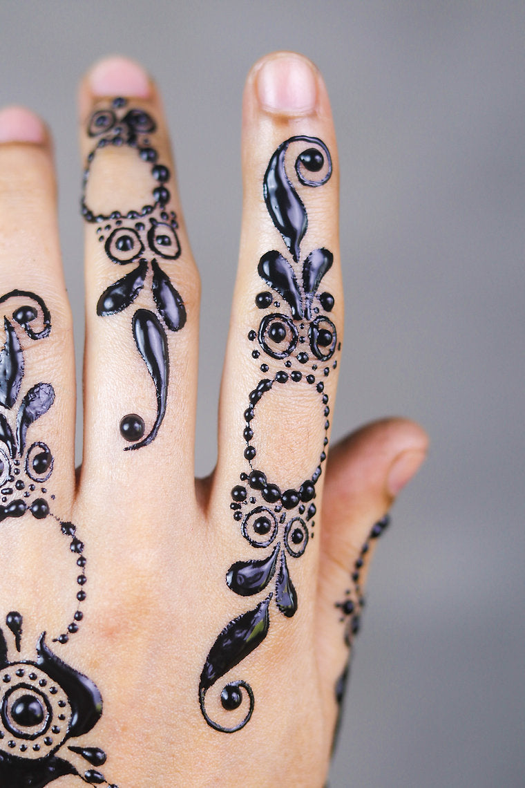 Hand with intricate black henna designs on fingers against a gray background