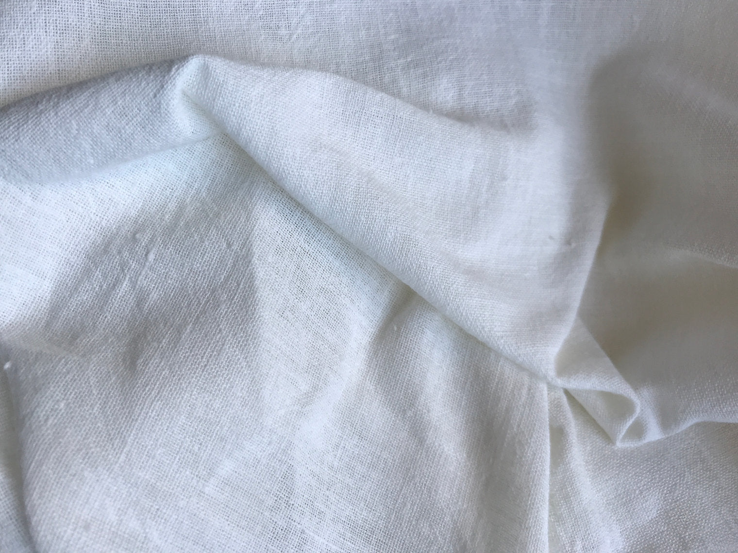 Close-up of white fabric with folds on a light gray background