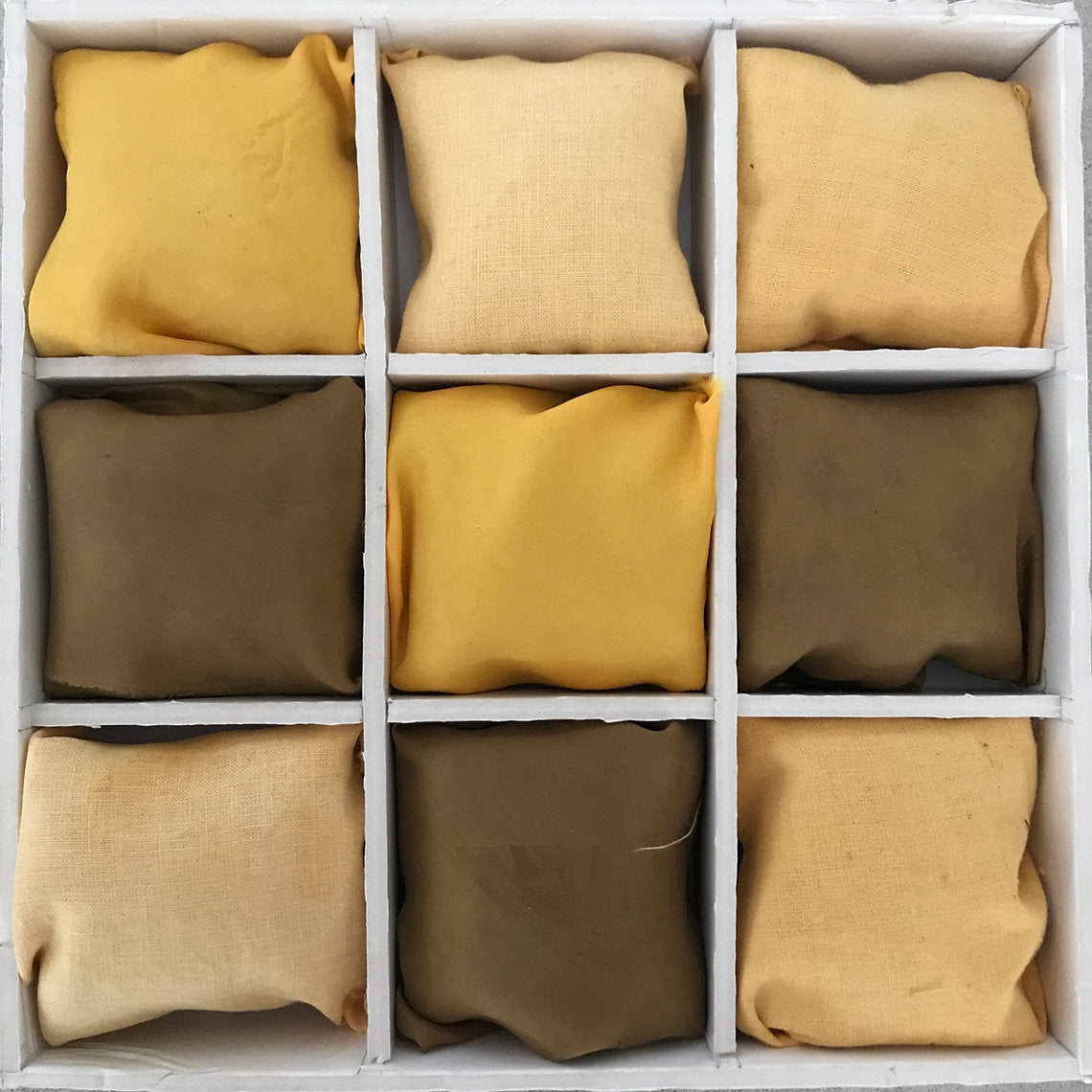 Nine square fabrics dyed Kamala Powder (Mallotus philippinensis) filled with yellow and brown fabric swatches arranged in a grid.