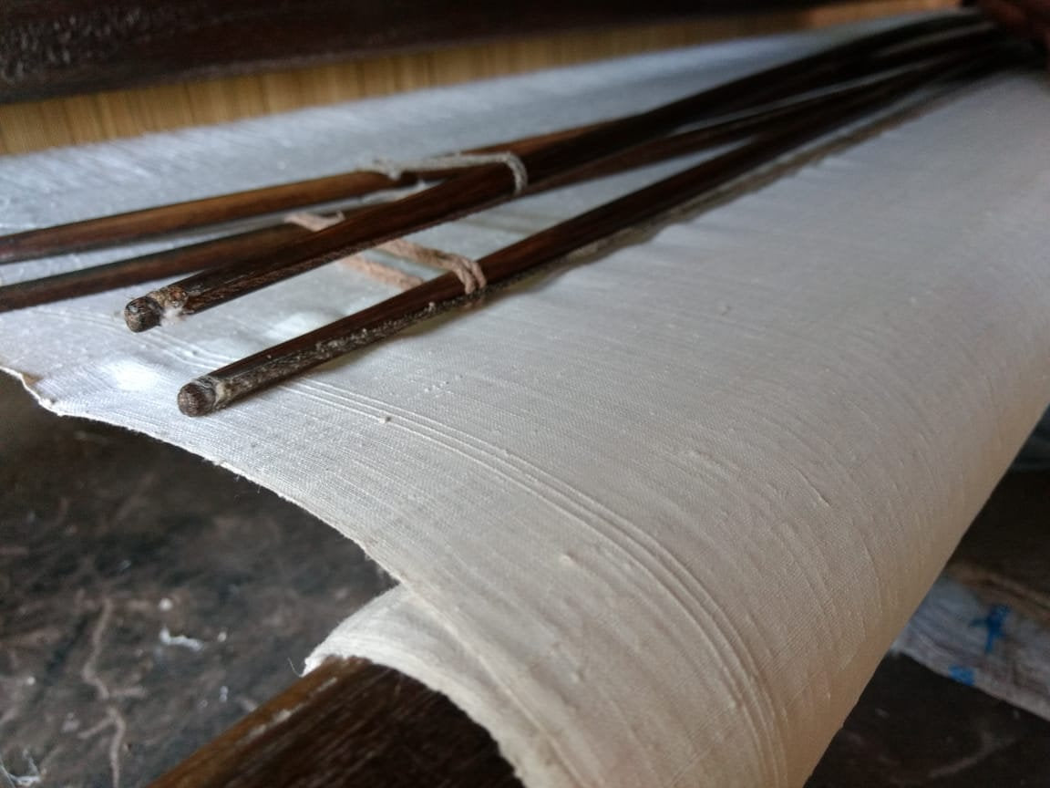 Three wooden sticks tied together on a roll of paper