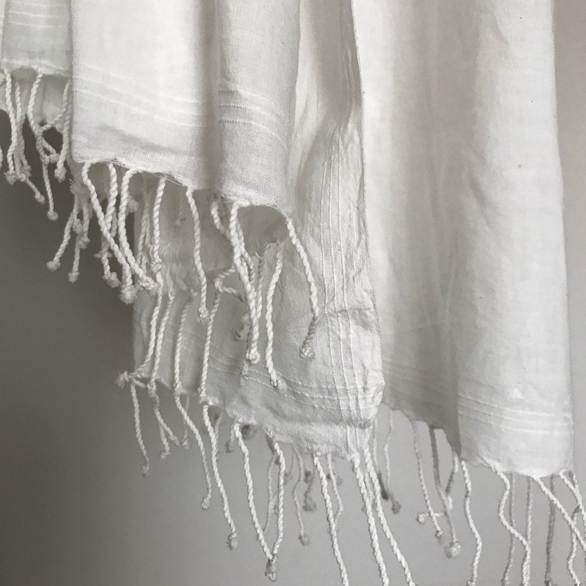 Close-up of a white textured white cotton shawl on a neutral background