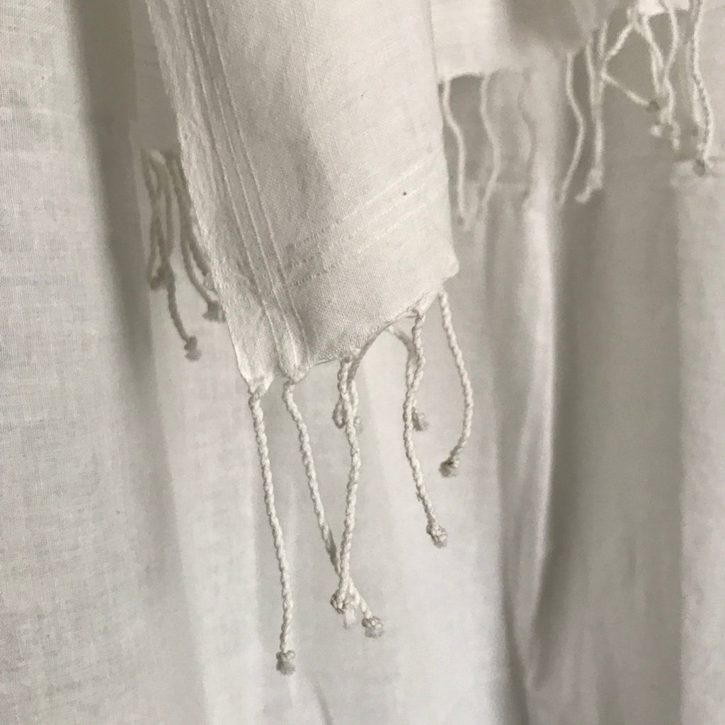 Close-up of a textured fabric with tassels on a light gray background