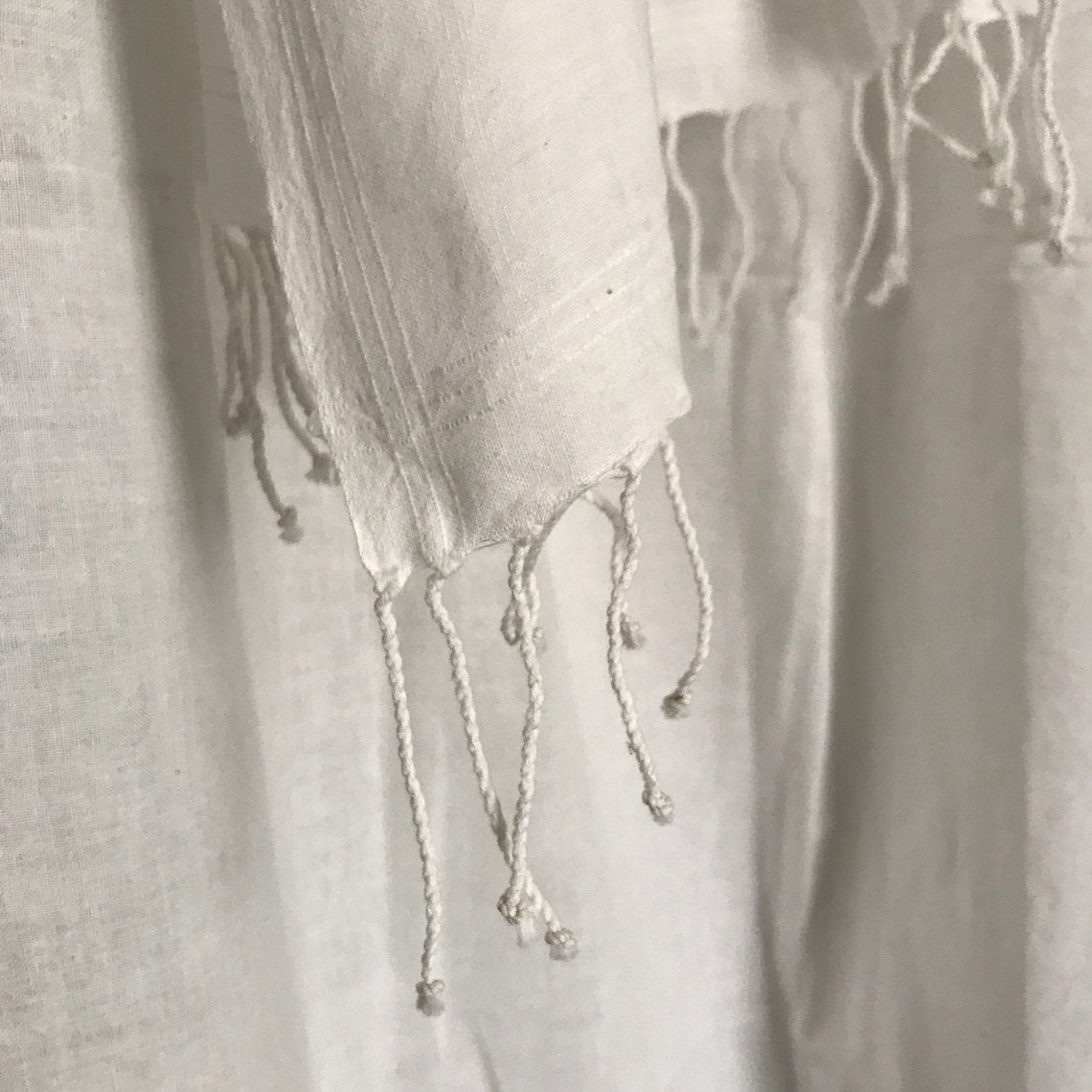 Close-up of a textured fabric with tassels on a light gray background