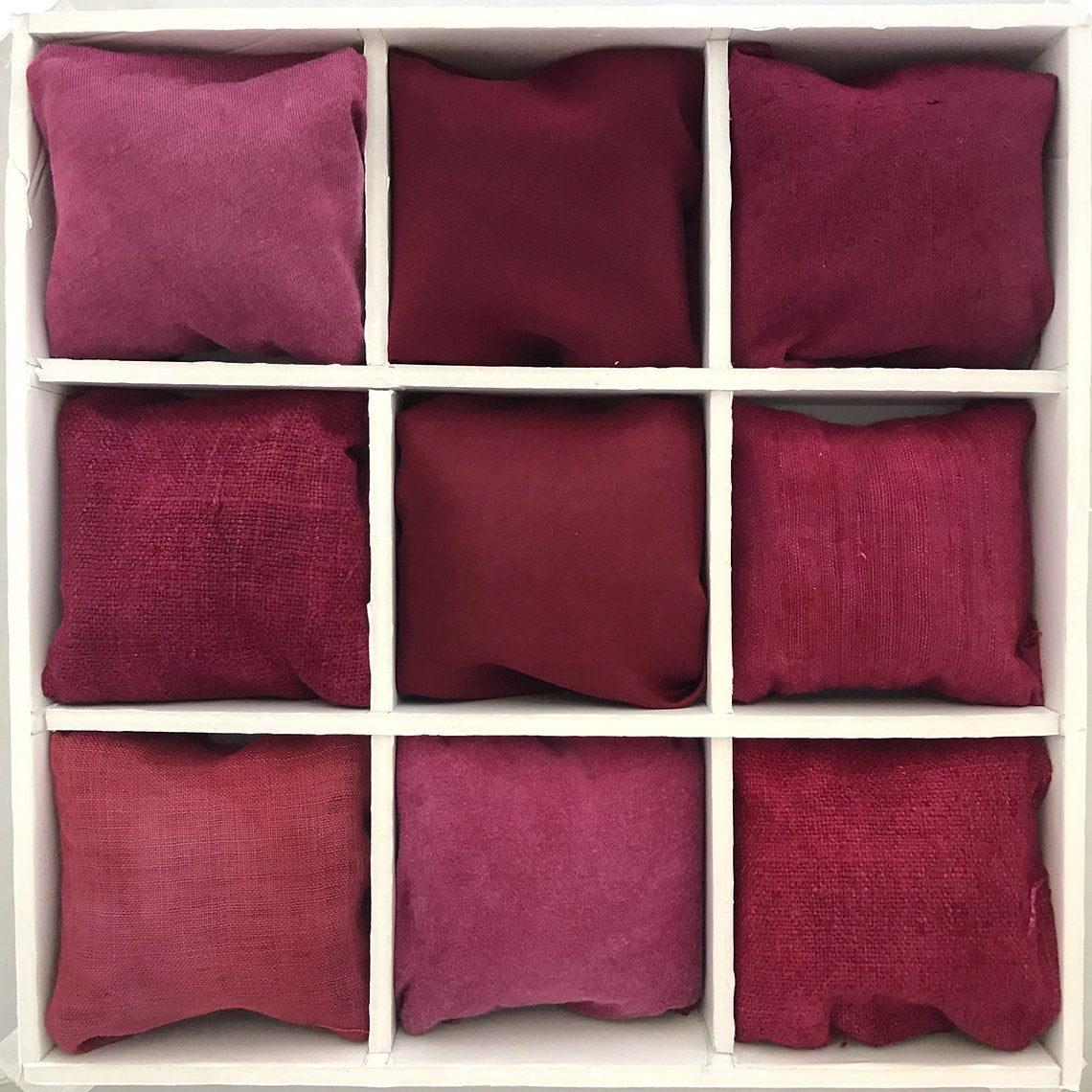 Nine red pillows dyed with Lac Extract (Laccifer lacca) arranged in a 3x3 grid on a white background