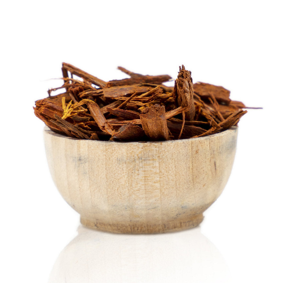 Wooden bowl filled with Logwood Chips (Haematoxylum campechianum) dried herbs on a white background