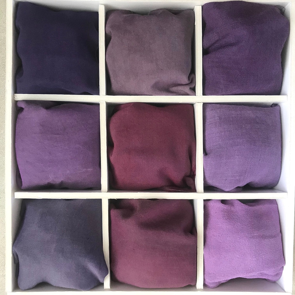 Nine purple fabric swatches dyed Logwood Extract (Haematoxylum campechianum) arranged in a 3x3 grid.