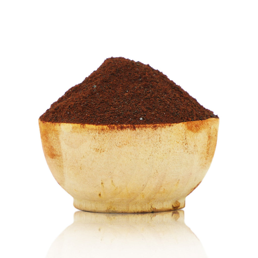 Wooden bowl filled with dark brown powder on a white background