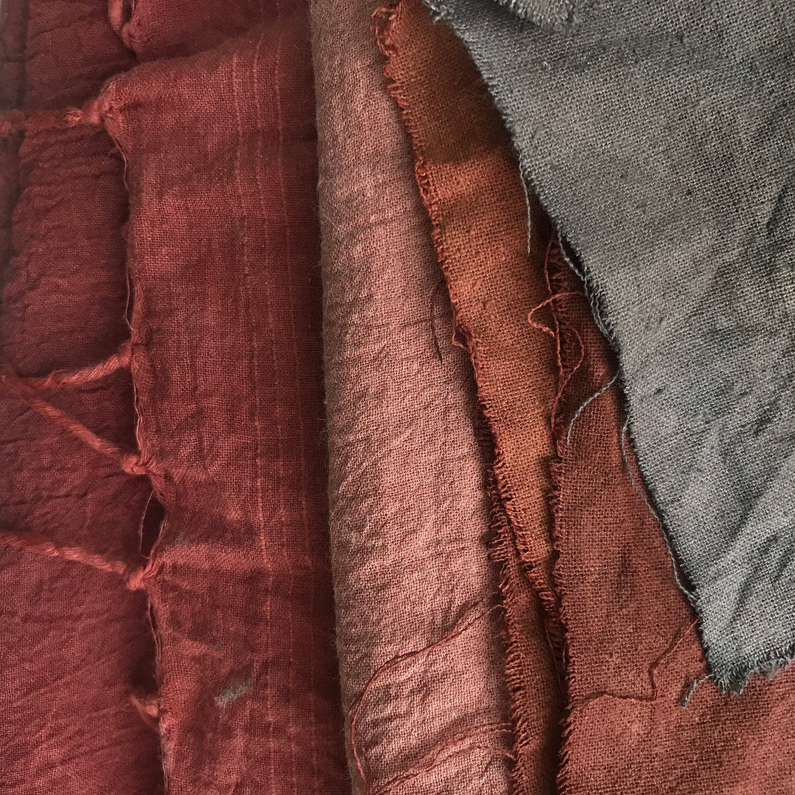 Close-up of textured fabric swatches in red, brown, and gray.