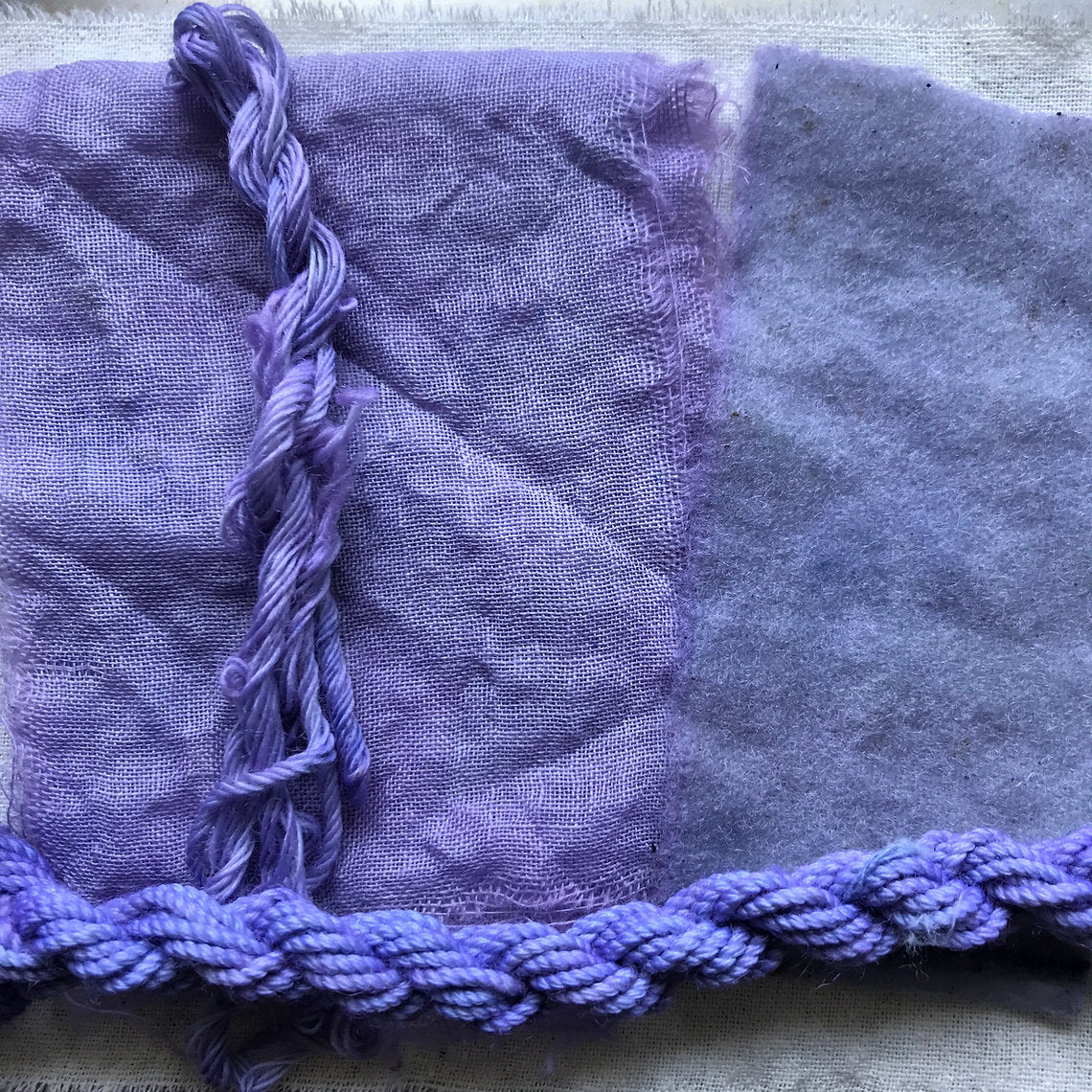 Purple fabric with tassels on a textured surface