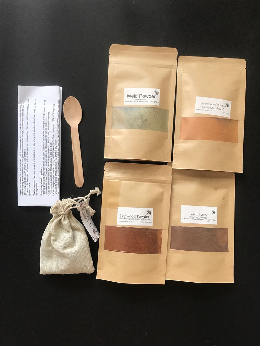 Four brown paper bags with labels, a wooden spoon, and a small white pouch on a black background.