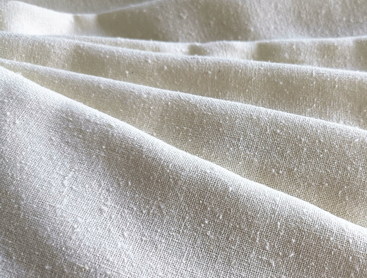 Close-up of textured beige silk woven fabric with folds