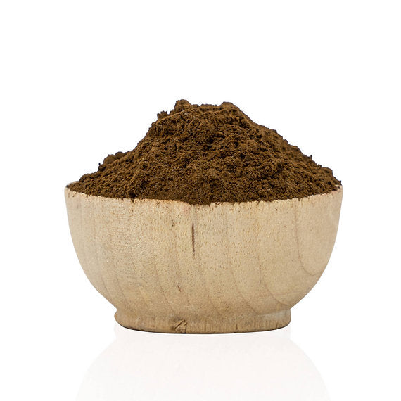 Wooden bowl filled with dark brown powder on a white background