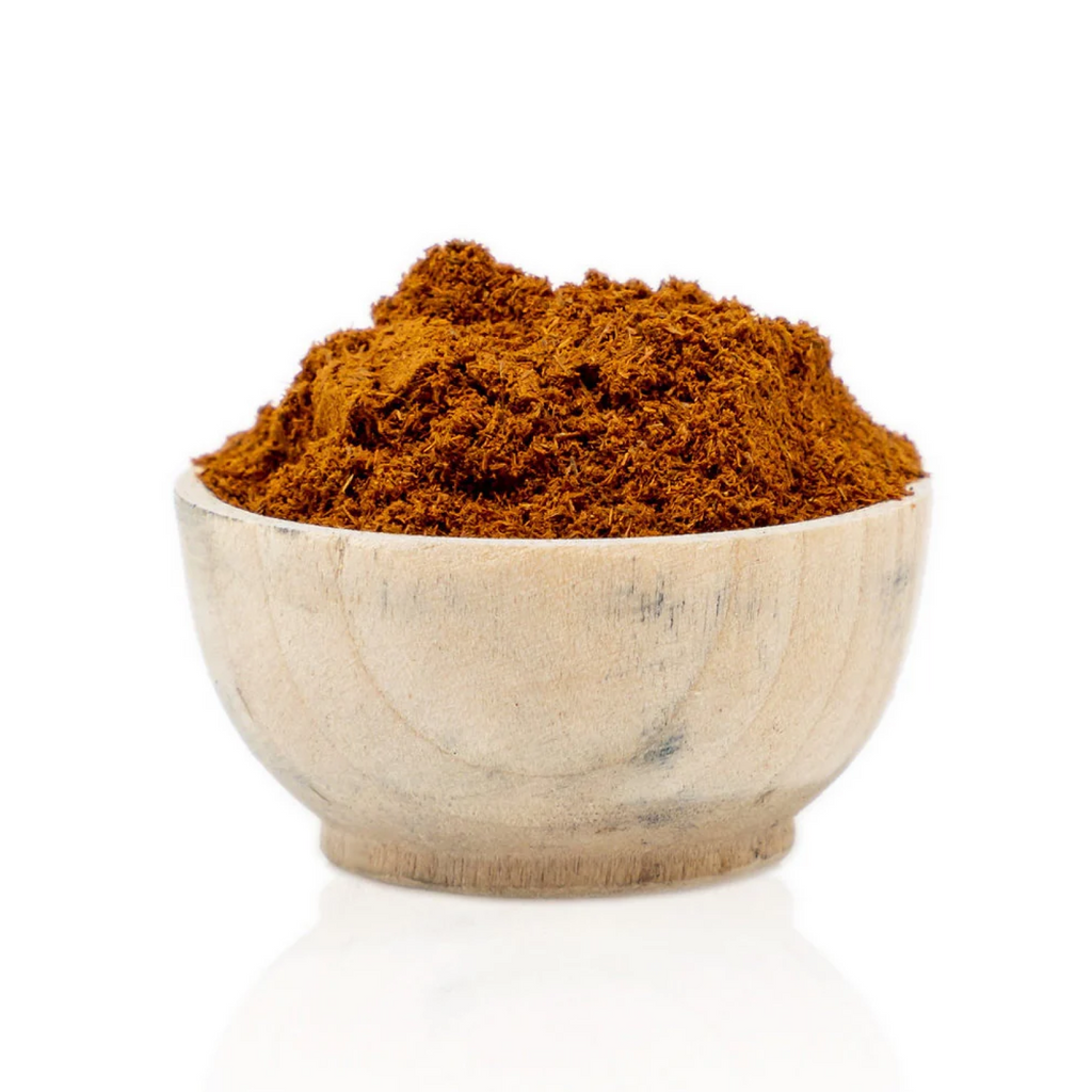 Wooden bowl filled with red powder on a white background